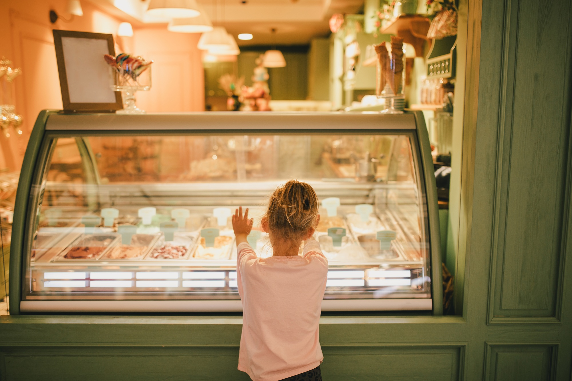 Cute girl standing near ice-cream shop, choosing ice-cream.