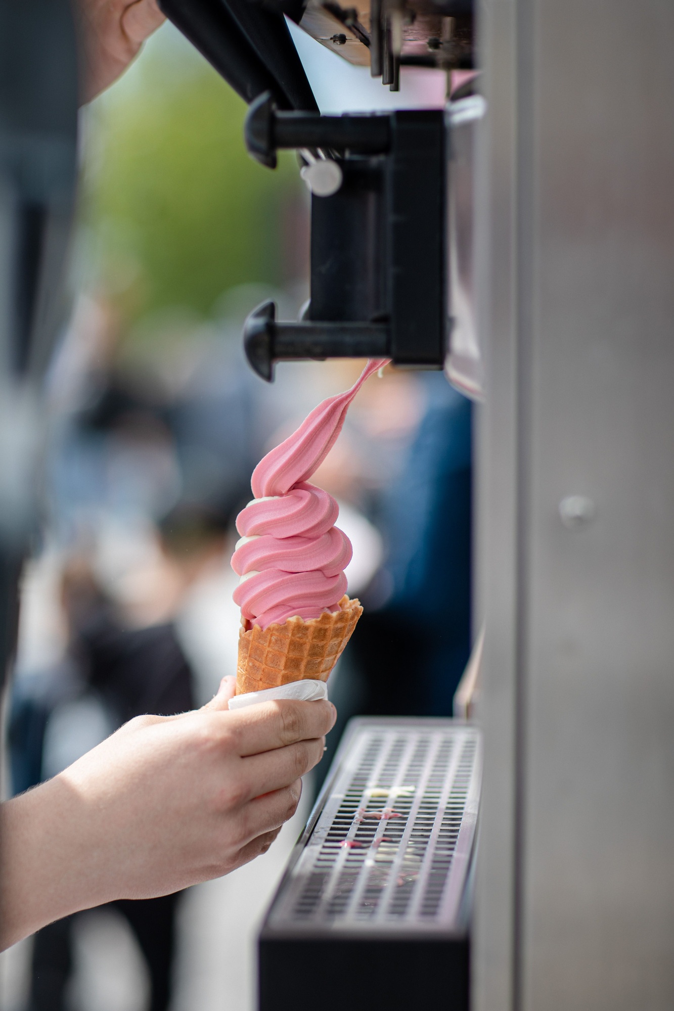 Vertical view of a person's hand holding an ice-cream from the machine